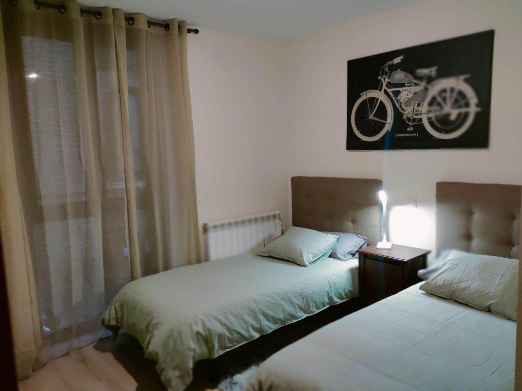 エステリ・ダネウにあるApartament Ca La Nenaのベッドルーム1室(ベッド2台付)が備わります。壁に自転車の写真が飾られています。