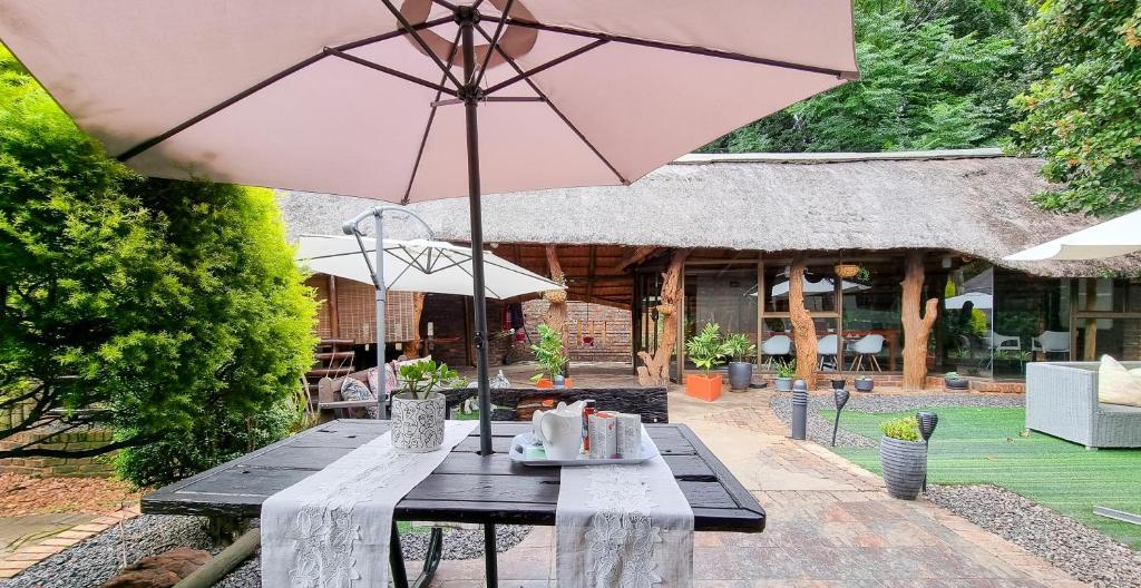 un tavolo da picnic con ombrellone su un patio di Pari Guest House a Middelburg