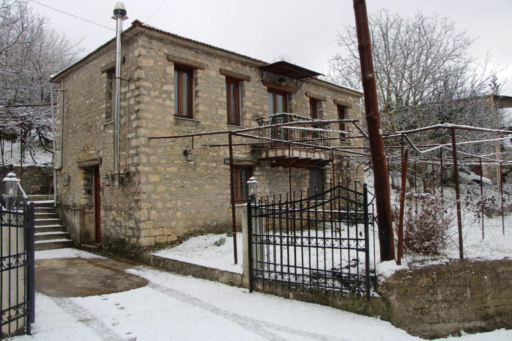 una vecchia casa di mattoni con un cancello nella neve di Gorianades Traditional House a Gorianádhes