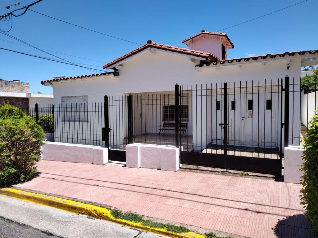 una casa blanca con una valla negra en Chalet Saboya en La Falda