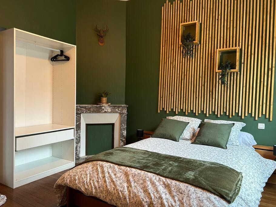 a bedroom with a bed with green walls and a fireplace at Au fil des étoiles in Selles-sur-Cher