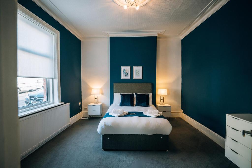a bedroom with blue walls and a bed with two lamps at Freda House By Horizon Stays in Sunderland