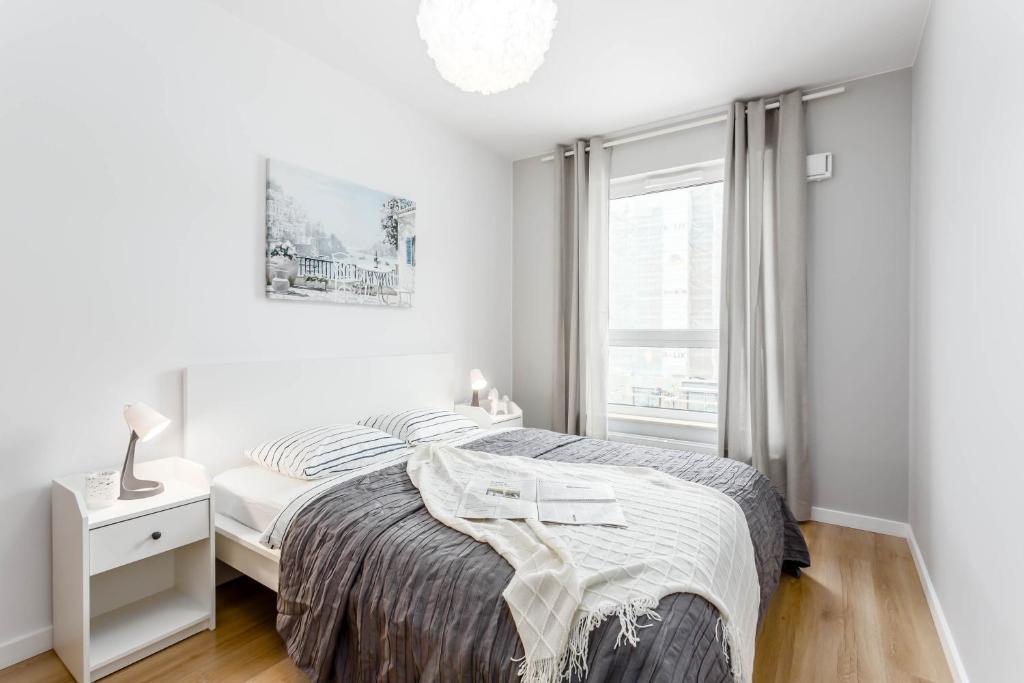een witte slaapkamer met een bed en een raam bij Enjoy! Ursus in Warschau