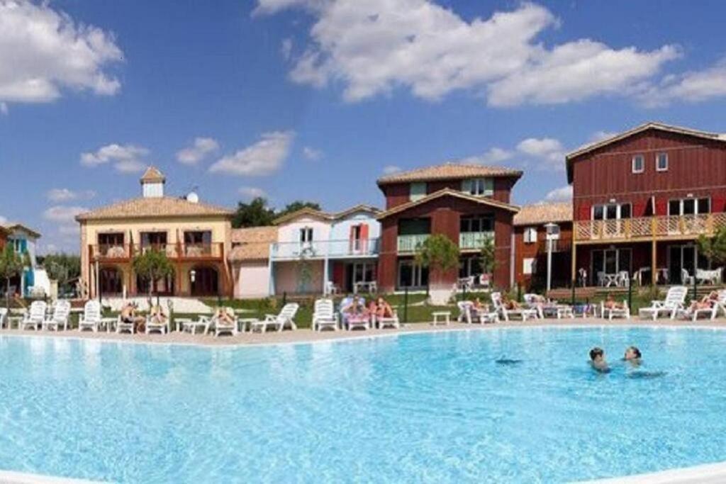 een groot zwembad met mensen in het water bij Appartement avec piscine sur le Bassin d'Arcachon in Le Teich