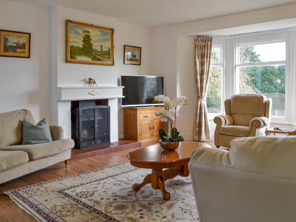 a living room with a fireplace and a tv at Springdale Farmhouse in North Burton
