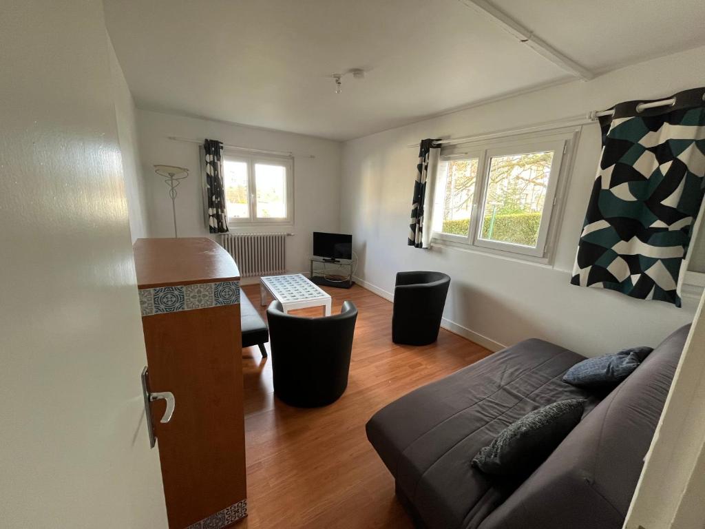 a living room with a couch and a table at Logement neuf en face de la forêt. Accès cour. in Bagnoles de l&#39;Orne