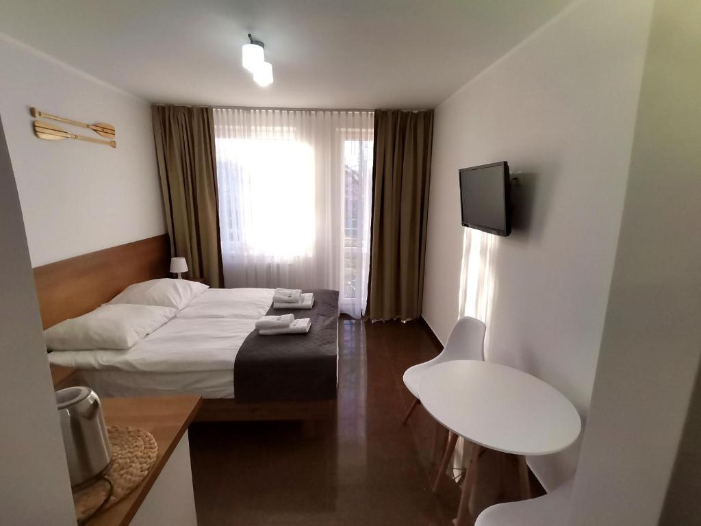 a small hotel room with a bed and a television at Apartament Planeta 110 Mielno in Mielno