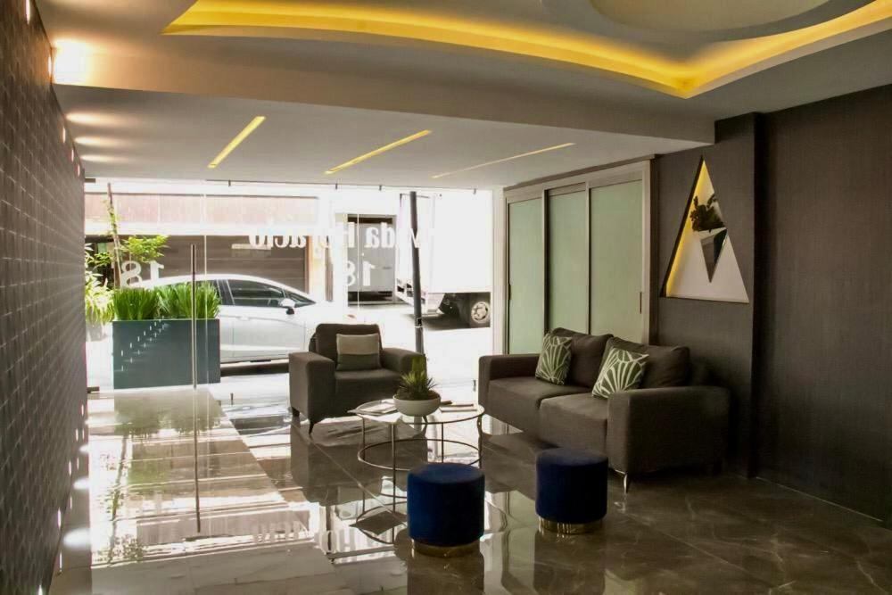 A polished lobby lounge with sofas, blue stools and a glass street frontage.