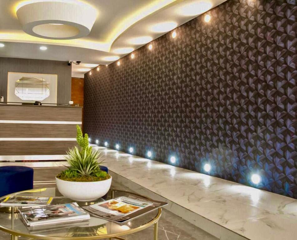 A polished lobby with a reception desk, patterned feature wall and seating table.