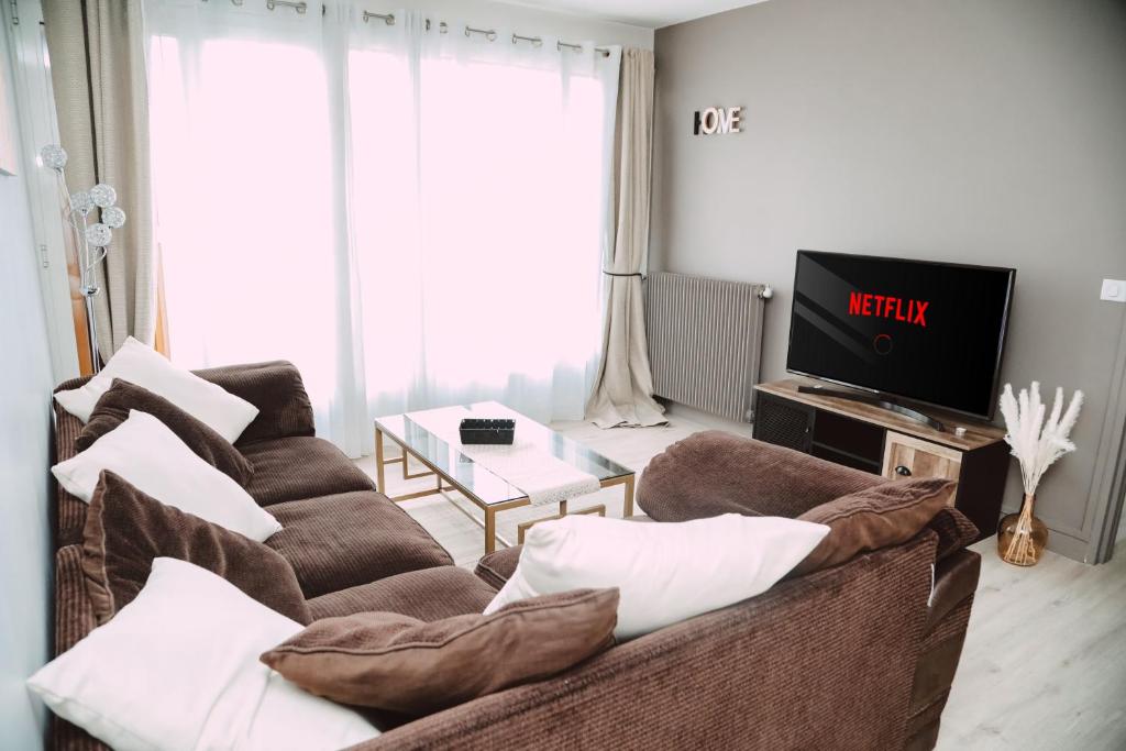 salon z kanapą i telewizorem w obiekcie Le nid douillet w mieście Villemomble