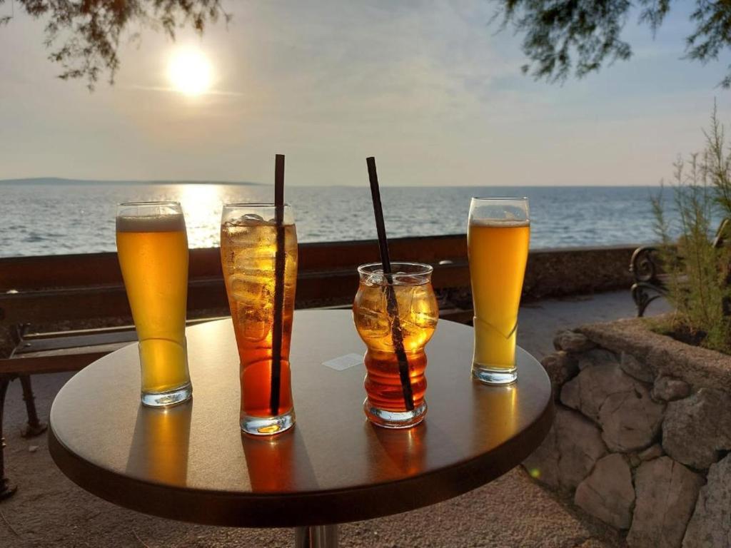 four glasses of beer on a table near the ocean at Eleonora in Banjole