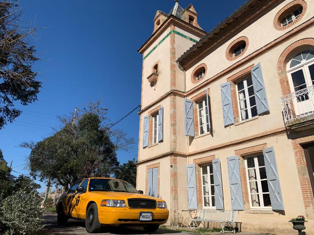 a yellow car parked in front of a building at Le Moulin du Carla in Lavaur