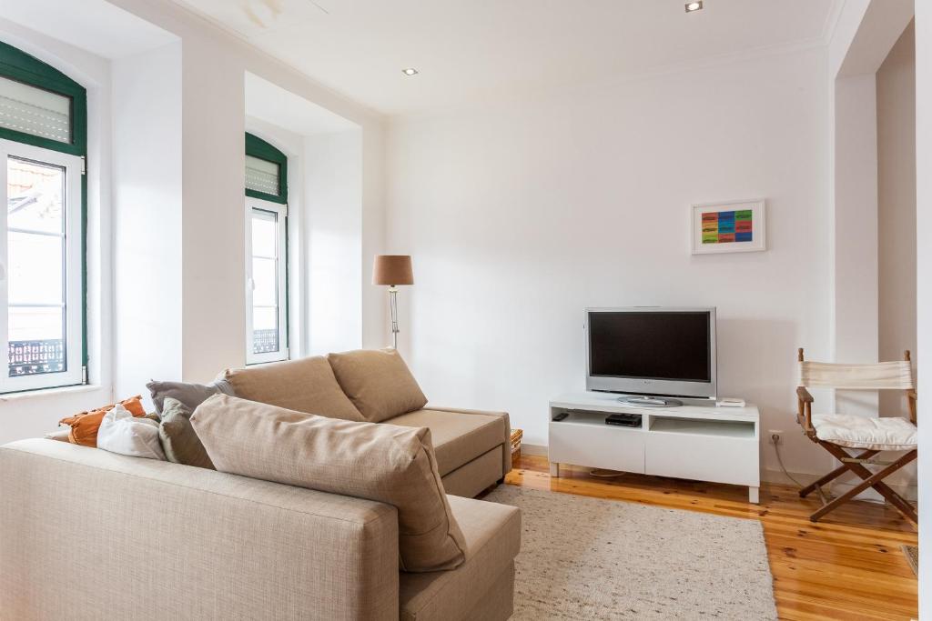 een woonkamer met een bank en een tv bij Apartment Príncipe Real Area in Lissabon