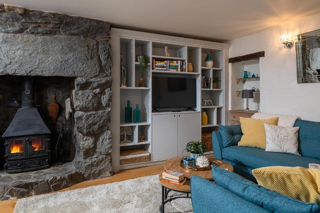 sala de estar con sofá azul y chimenea de piedra en Ysgoldy, en Llanfor