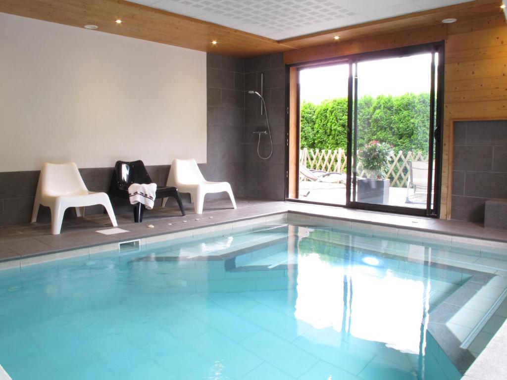 a swimming pool with two chairs and a table at Gîte Balnéo Au Coeur des Alpes in Taninges