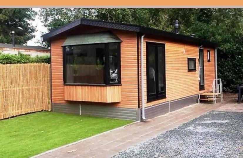 a tiny house with a large window in a yard at Het Eikenhuisje in Putten; huisje op de Veluwe. in Putten