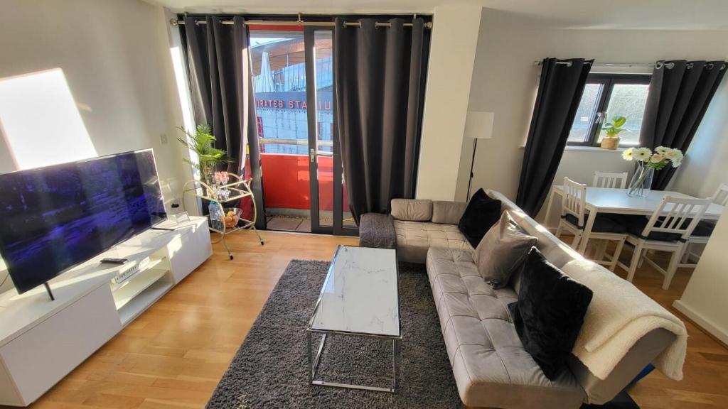 uma sala de estar com um sofá e uma televisão de ecrã plano em Luxury Gem By Emirates Stadium - Ultimate Fan Experience em Londres
