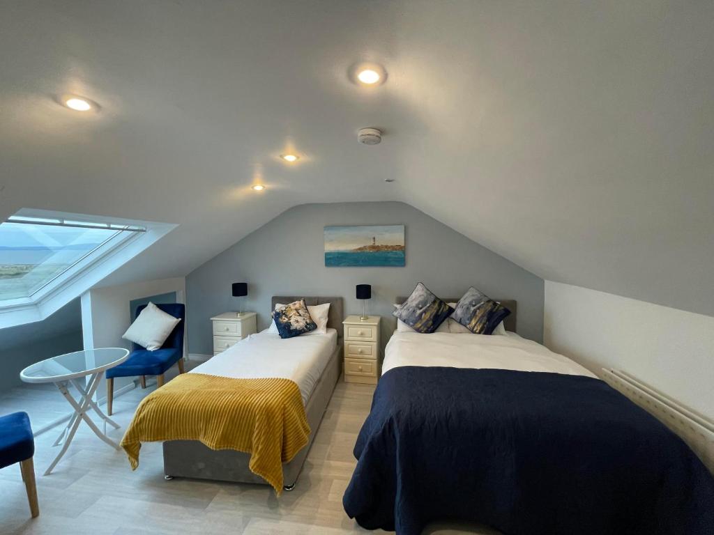 a attic bedroom with two beds and a table at SeaClusion Barna in Barna