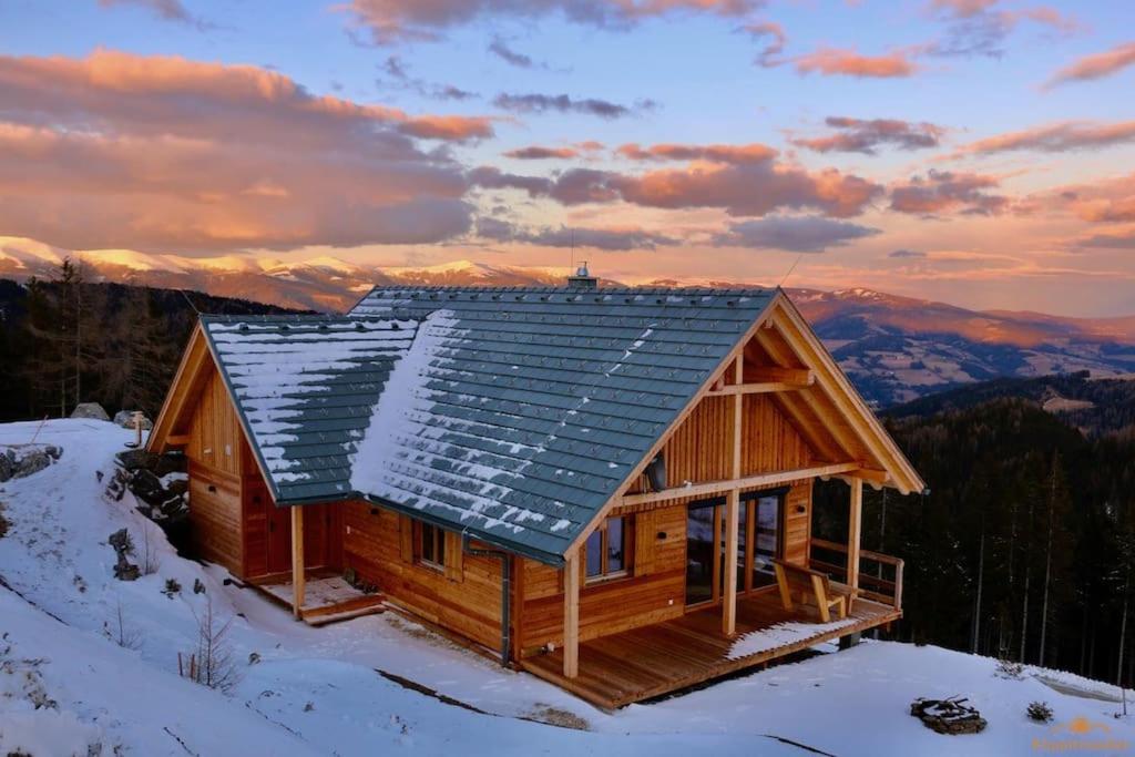 eine Blockhütte mit Schnee auf dem Dach in der Unterkunft Almchalet Klippitzzauber in Bad Sankt Leonhard im Lavanttal