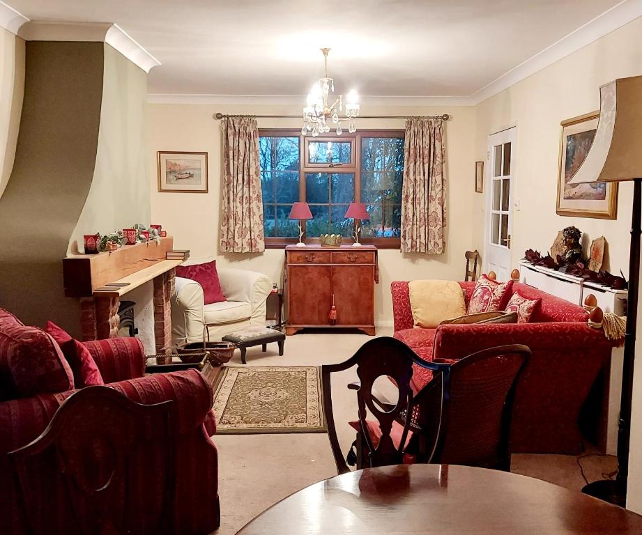 ein Wohnzimmer mit roten Möbeln und einem Tisch in der Unterkunft The Captain's Cottage at Climping in Climping