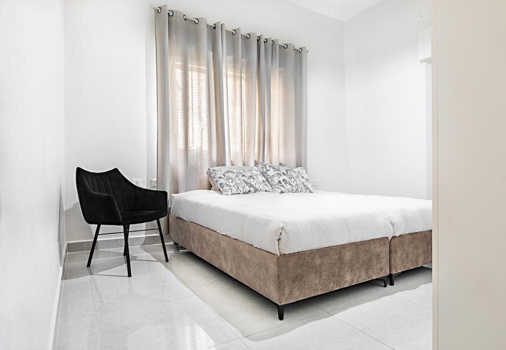 - une chambre avec un lit et une chaise à côté d'une fenêtre dans l'établissement Rechavia Apartment, à Jérusalem