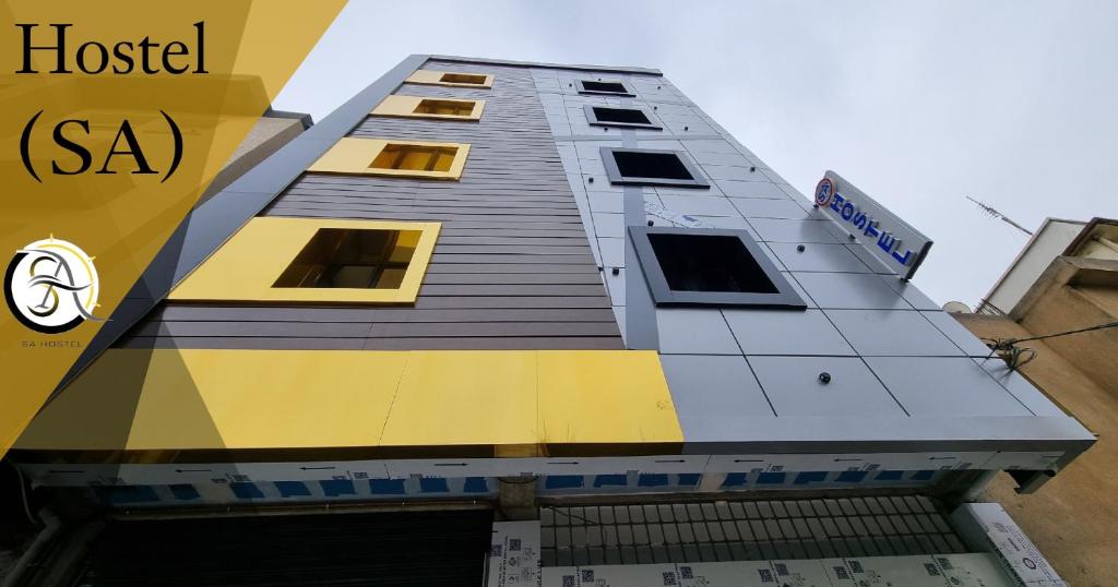 un edificio alto con amarillo y gris en Hostel SA Bab Ezzouar en Le Lido