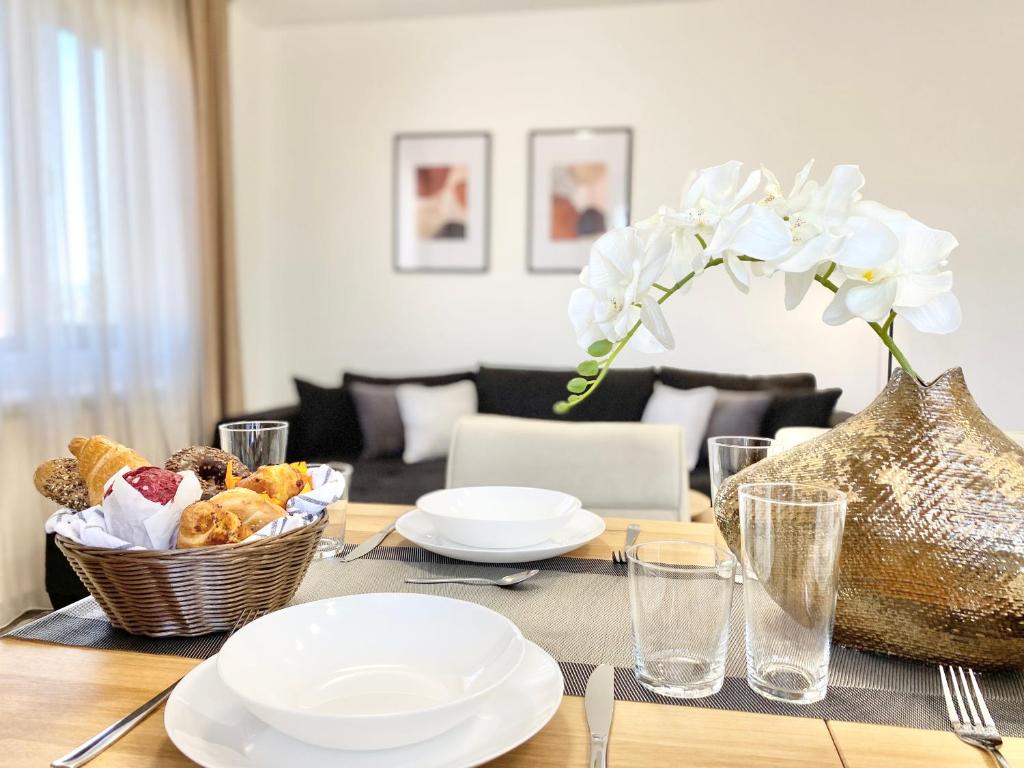 a dining room table with white plates and a basket of food at Central Apartment for 4 Guests Next to State Opera in Stara Zagora