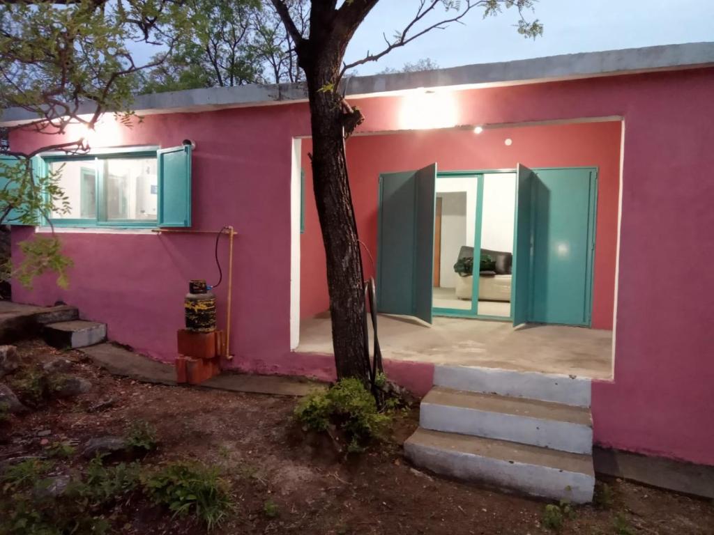 una casa rosa con puertas verdes y un árbol en La Higuerita 