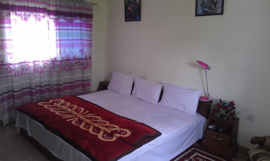 Un dormitorio con una cama blanca con una manta roja. en Konkon Wonderland, en Accra
