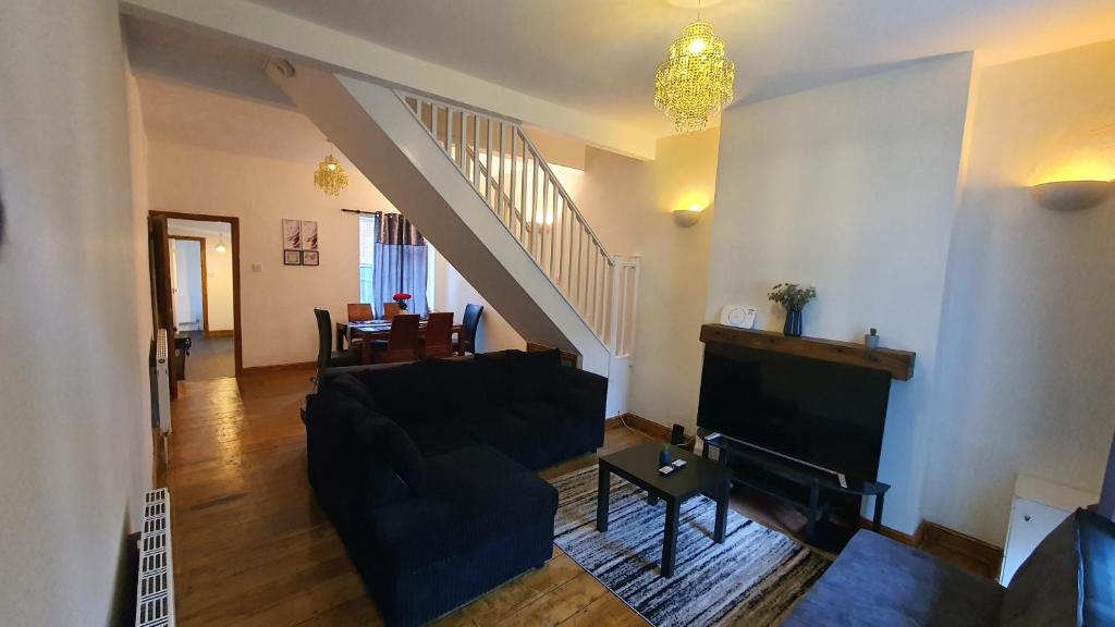 a living room with a black couch and a staircase at Spacious 2 Bedroom Home in Birmingham in Birmingham