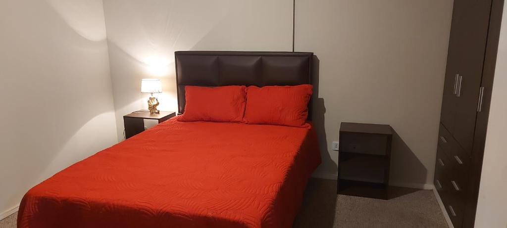 a bedroom with a red bed with two red pillows at Departamento 3 D. Cochabamba in Cochabamba