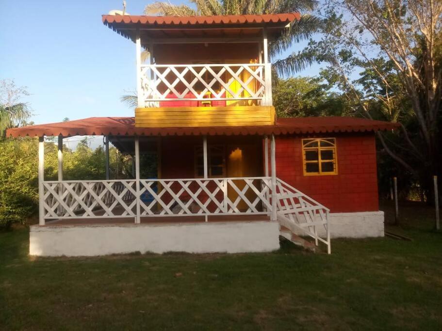 a small red house with a white fence around it at ¡VILLA AZUL! LUGAR ENCANTADOR A 60 METROS DEL MAR :o ;) in Necoclí