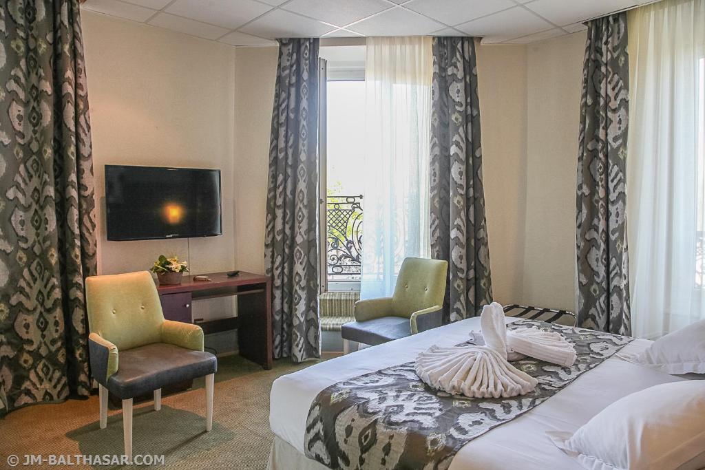 ein Hotelzimmer mit einem Bett, 2 Stühlen und einem TV in der Unterkunft Hôtel Le Bristol Strasbourg Gare in Straßburg