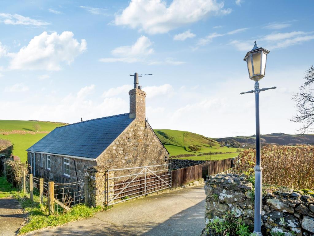 una vieja iglesia de piedra con una cruz en el techo y una luz de la calle en Hafod, en Llanengan