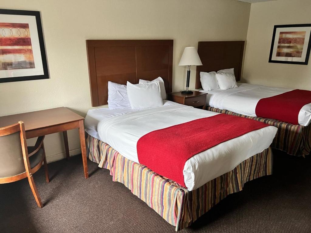 a hotel room with two beds and a table and a desk at Days Inn By Wyndham Pigeon Forge South in Pigeon Forge