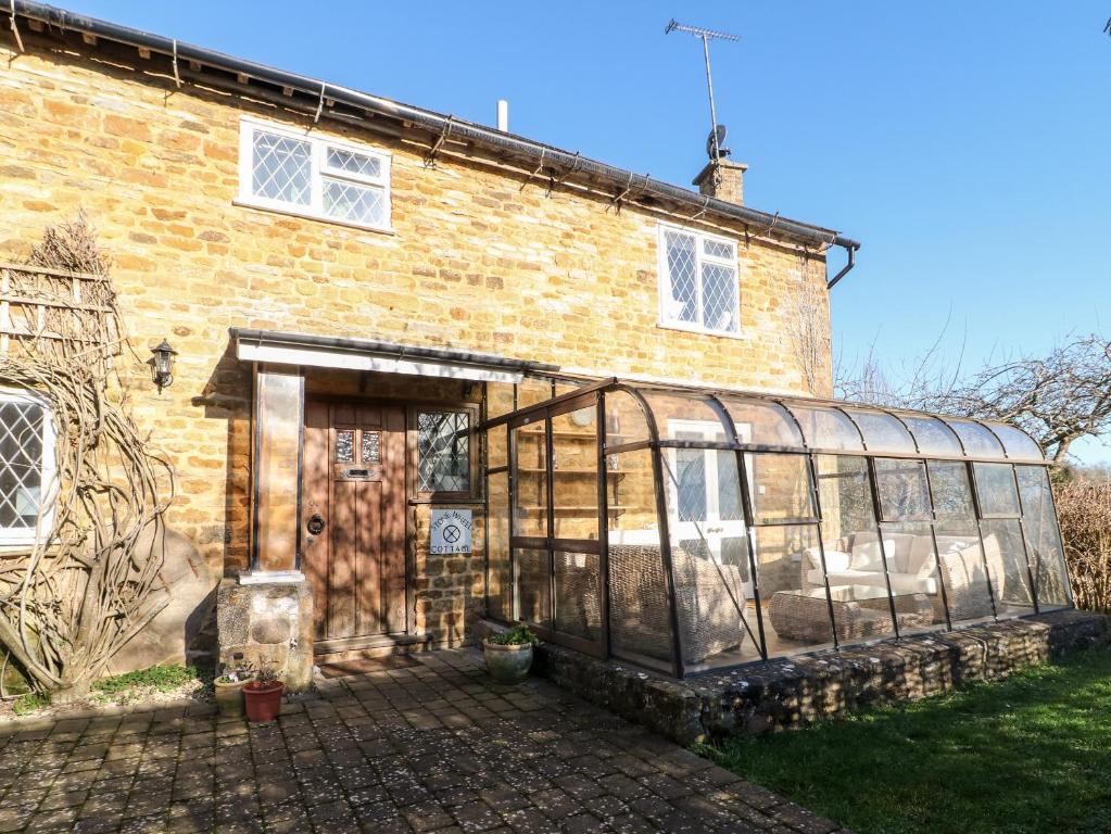 a house with a greenhouse on the side of it at Stone Wheel Cottage in Hook Norton