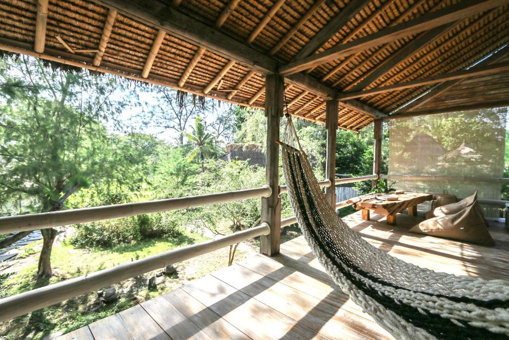 a hammock on a porch of a house with a view at MaoMeno Yoga Resort in Gili Meno