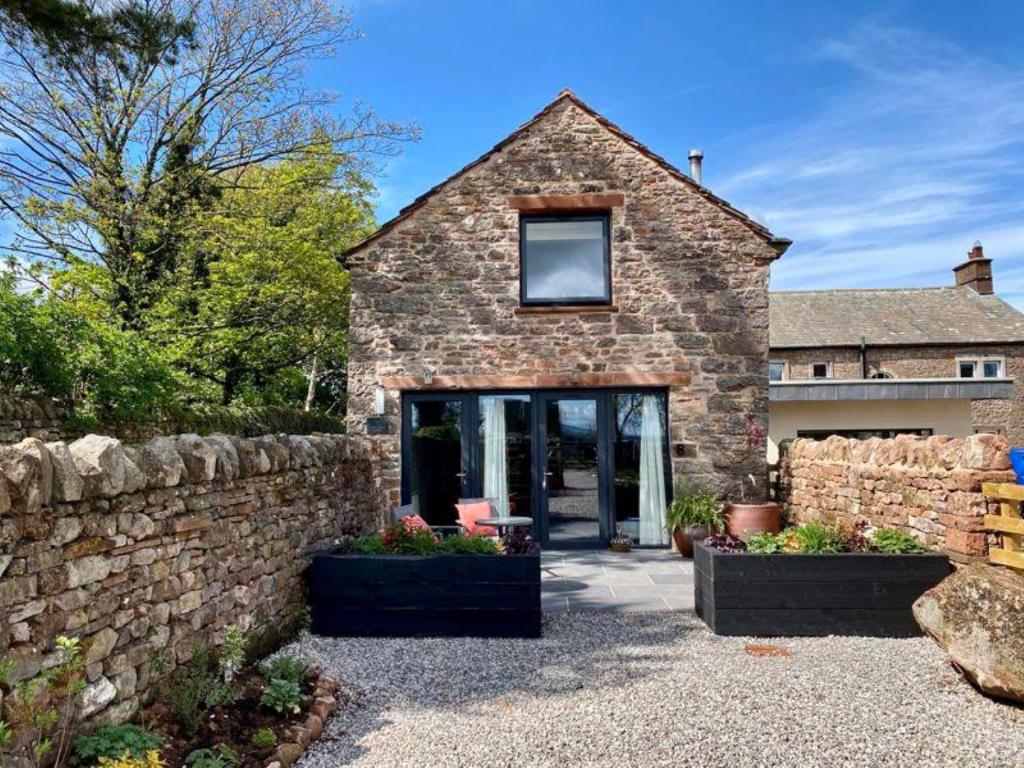 a stone house with a stone wall at Stylish & cosy barn minutes from the Lake District in Penrith