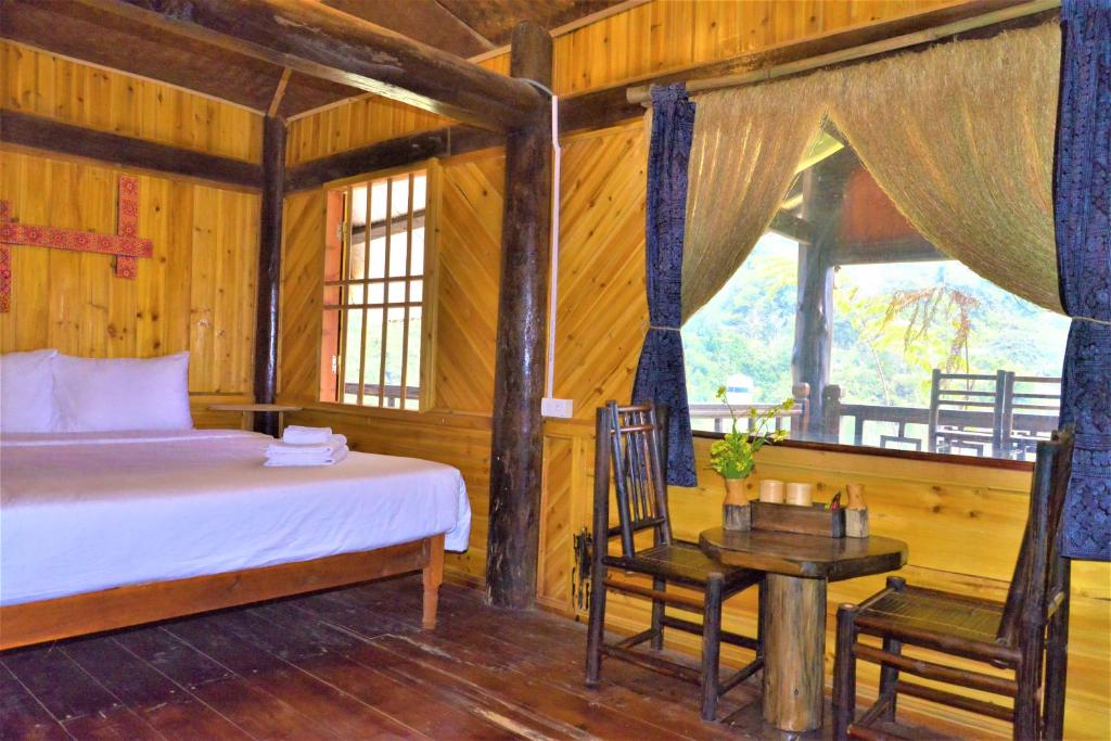 um quarto com uma cama, uma mesa e cadeiras em H'mong Eco House em Lao Cai