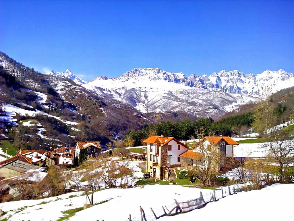 ein Dorf im Schnee mit Bergen im Hintergrund in der Unterkunft Casas Rurales y Apartamentos La Hornera in Cosgaya