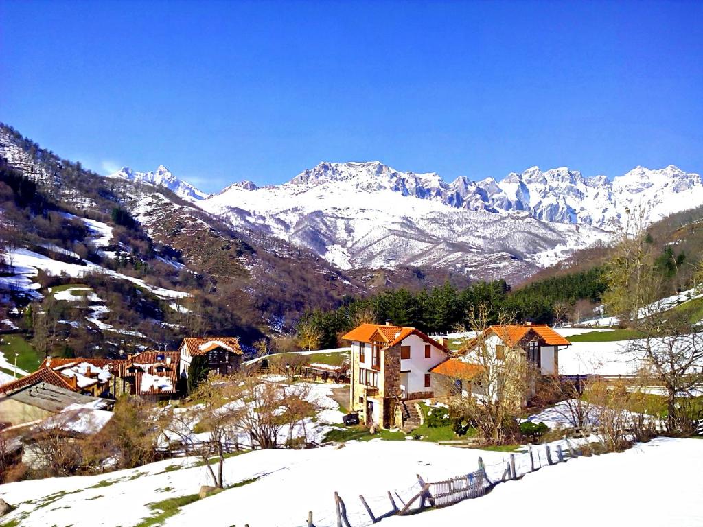 a village in the snow with mountains in the background at Casas Rurales y Apartamentos La Hornera in Cosgaya