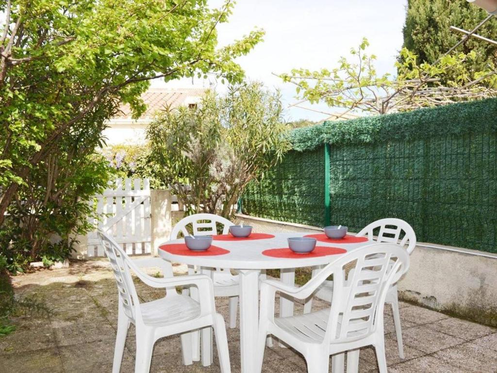 une table blanche et quatre chaises sur la terrasse dans l'établissement Charmant Pavillon Studio Mezzanine, Piscine, Plage à 200m, Parking Privé - Narbonne Plage - FR-1-229B-565, à Narbonne