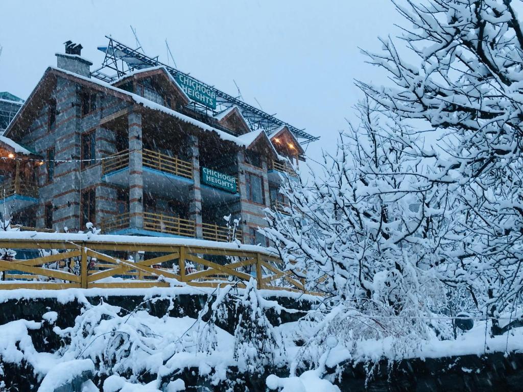 a building covered in snow with trees in front of it at Chichoga Heights in Manāli