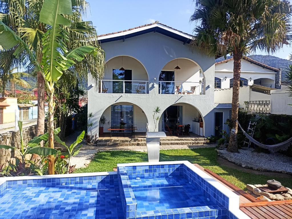 a villa with a swimming pool in front of a house at Pousada Quintal do Mar in Ubatuba