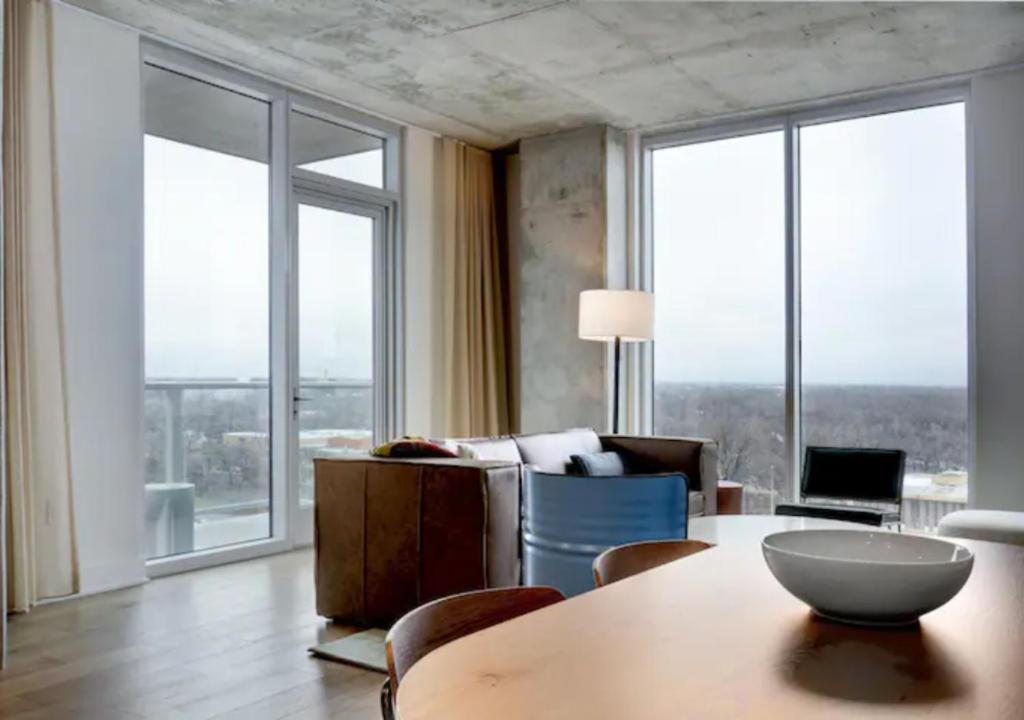 ein Wohnzimmer mit einem Tisch und einigen Fenstern in der Unterkunft Brand New - Spacious Luxury Condo, Steps from Lake & Rainey for 4 in Austin