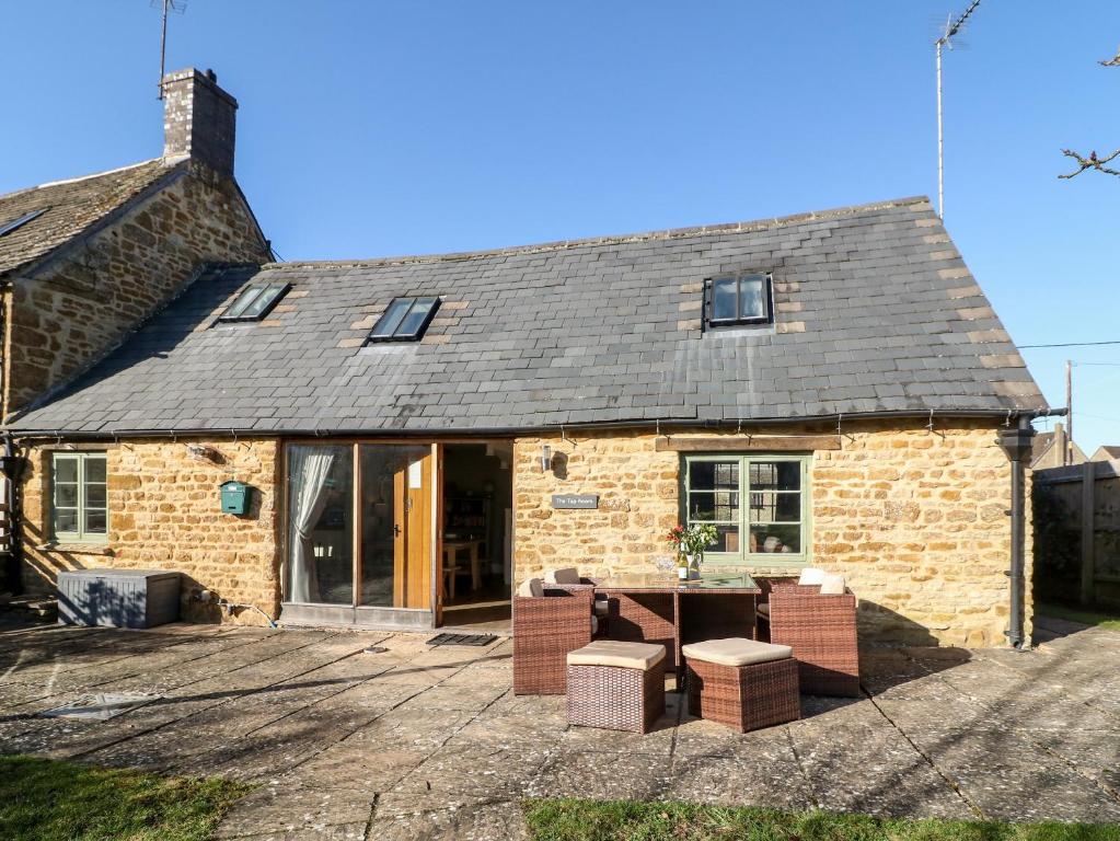 a stone cottage with a table and chairs in front of it at The Tap Room in Kingham