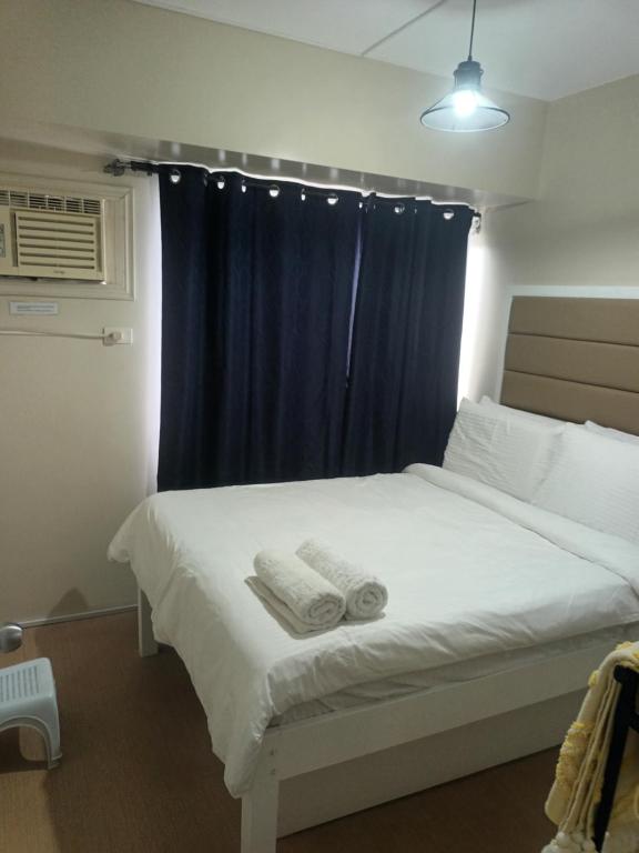 - une chambre avec un lit blanc et un rideau bleu dans l'établissement NICE CORNER AYALA 1 bedroom condo at heart of DAVAO CITY with hi speed wi fi internet, à Davao