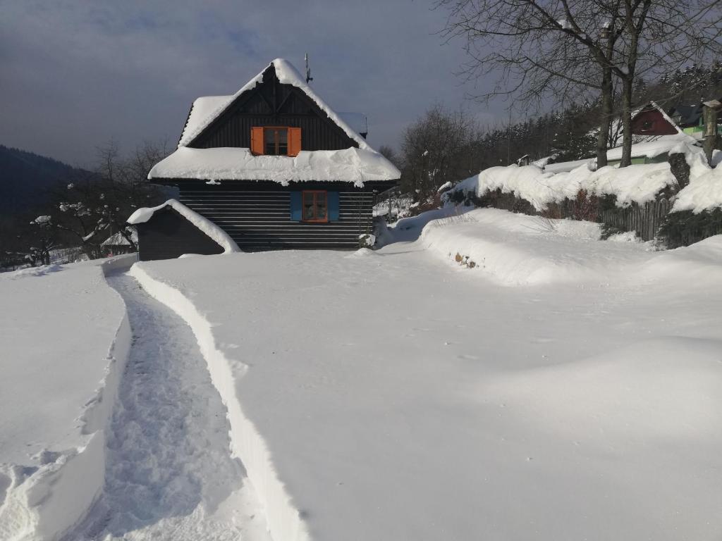 a house is covered in snow with a trail at Chata Kolmanovci in Oščadnica