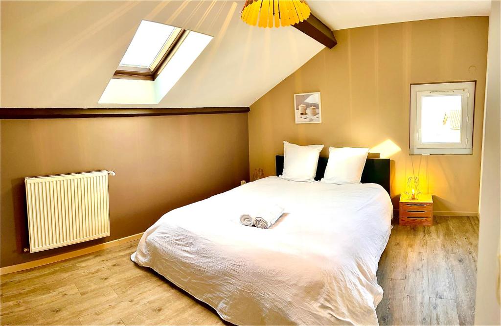 ein Schlafzimmer mit einem großen weißen Bett und einem Dachfenster in der Unterkunft Logement indépendant 1 à 2 chambres, idéal séjour Bourg en bresse in Péronnas