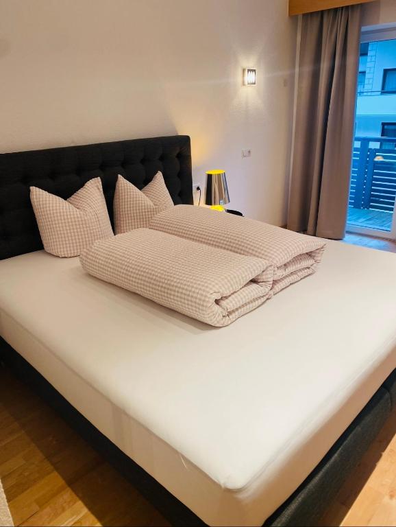 un letto con lenzuola e cuscini bianchi di Bei die Gstrein's a See